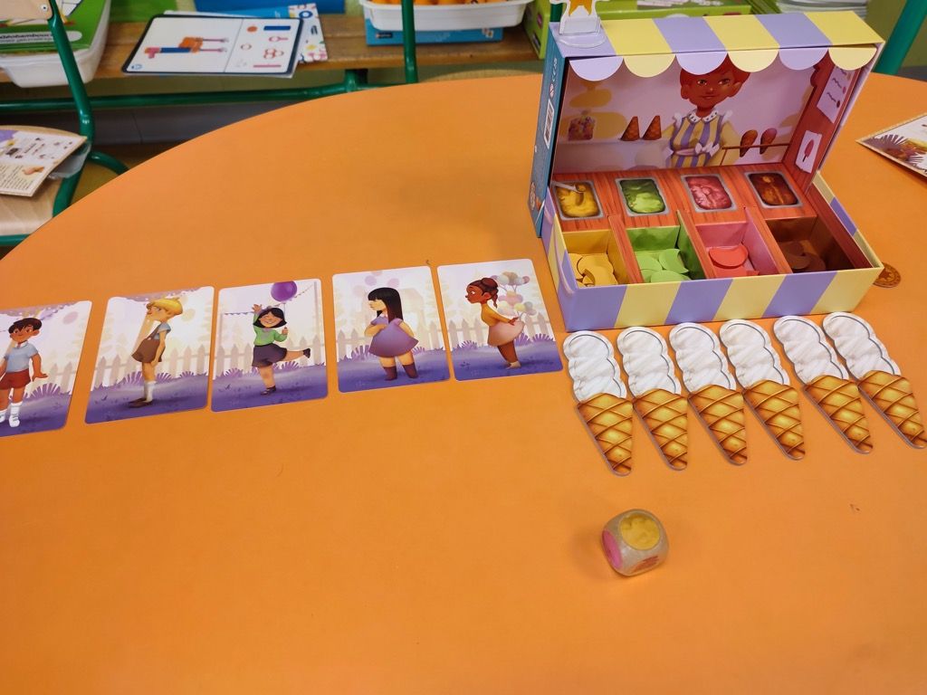 La mise en place du jeu : 6 cartes Enfant en attente, 6 cornets à remplir, 1 soleil positionné sur la première case du auvent et le dé Glacier.